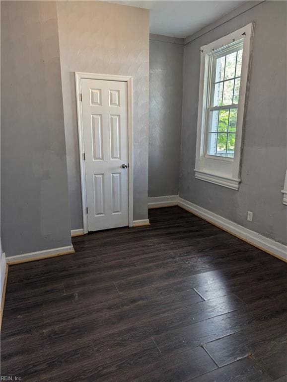 unfurnished room with baseboards and dark wood-style flooring