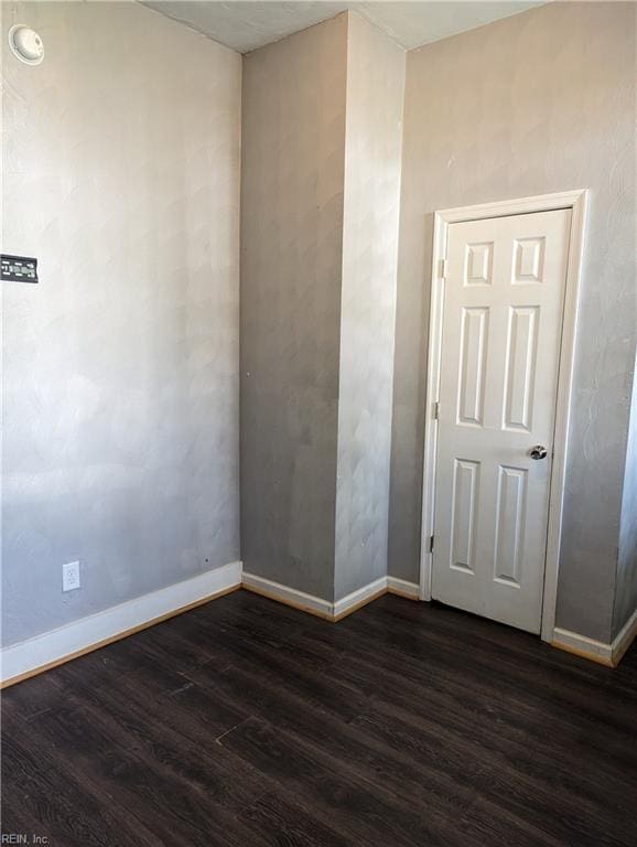 unfurnished room featuring dark wood-style floors and baseboards