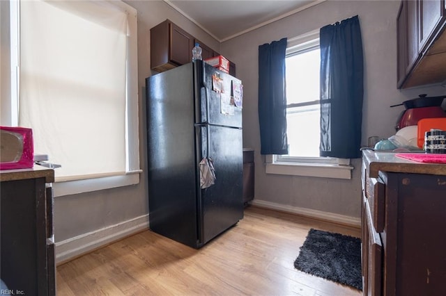 kitchen with light wood-style floors, baseboards, crown molding, and freestanding refrigerator