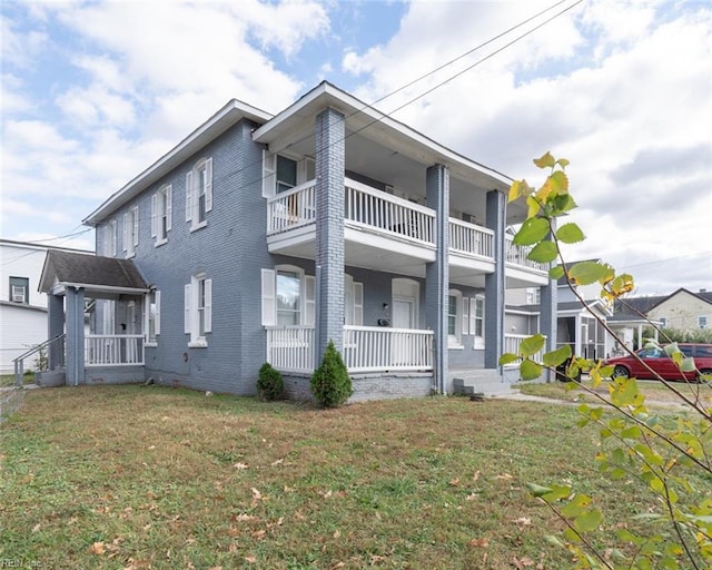 view of front facade with a balcony, covered porch, brick siding, and a front yard