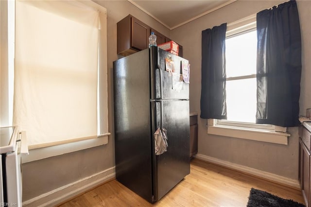 kitchen featuring light wood finished floors, baseboards, and freestanding refrigerator