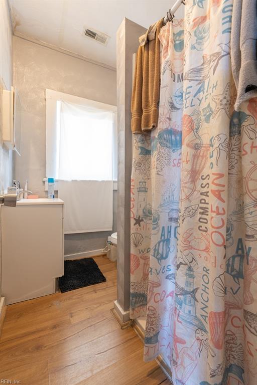 full bathroom with curtained shower, toilet, wood finished floors, vanity, and visible vents