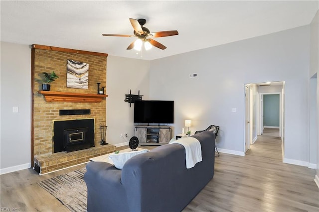 living room with baseboards, ceiling fan, and light wood-style floors