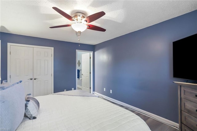 bedroom featuring a textured ceiling, baseboards, a closet, and wood finished floors