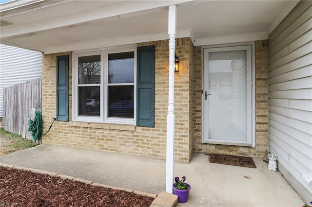 entrance to property with brick siding and fence