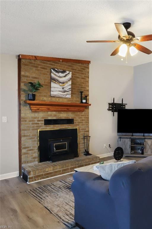 living area with a ceiling fan, a textured ceiling, baseboards, and wood finished floors