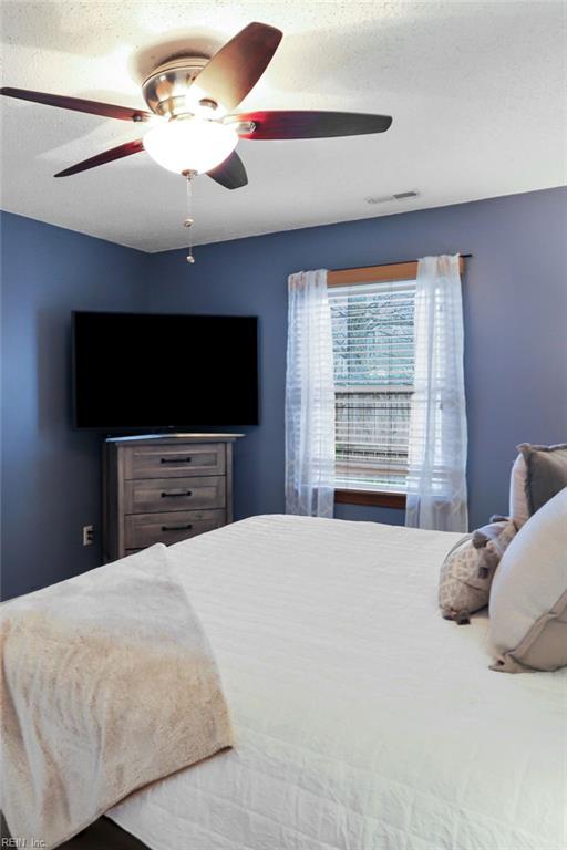 bedroom with a textured ceiling, visible vents, and a ceiling fan