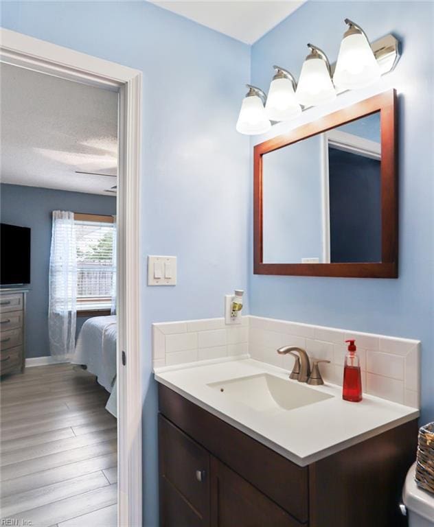 bathroom with tasteful backsplash, vanity, and wood finished floors