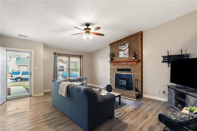 living room featuring visible vents, ceiling fan, wood finished floors, vaulted ceiling, and a textured ceiling