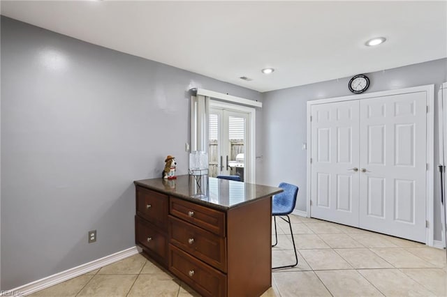 kitchen with baseboards, a peninsula, light tile patterned flooring, and a kitchen breakfast bar