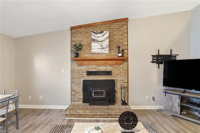 living area featuring a wood stove, baseboards, and wood finished floors