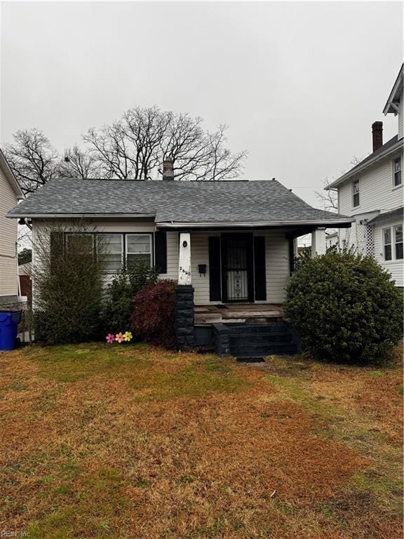 bungalow-style house featuring a front lawn and roof with shingles