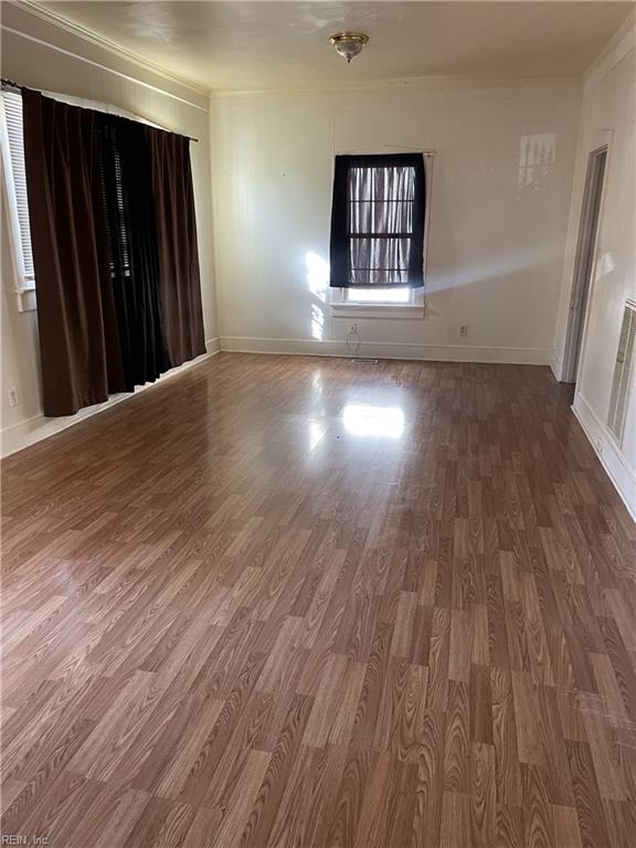 spare room with baseboards, wood finished floors, and ornamental molding