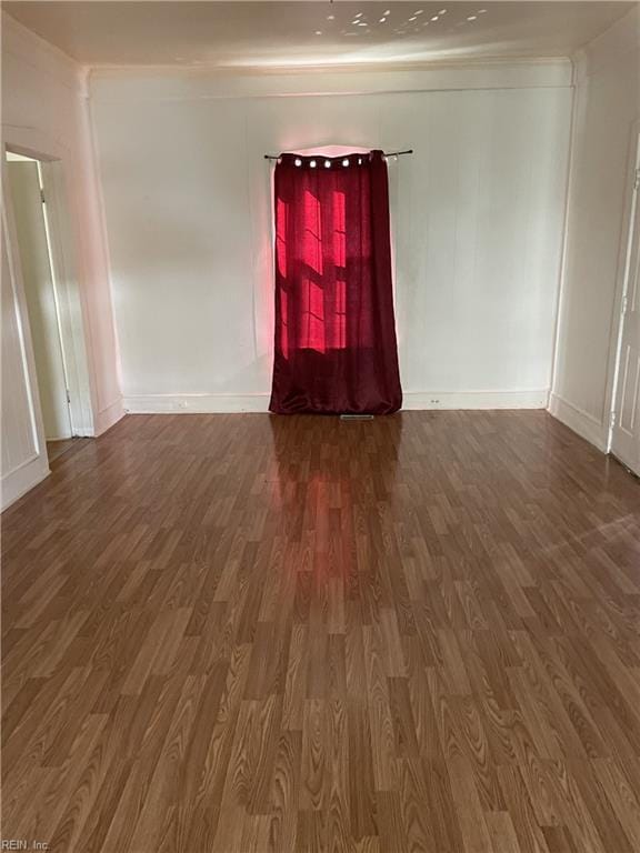 spare room featuring ornamental molding, baseboards, and wood finished floors