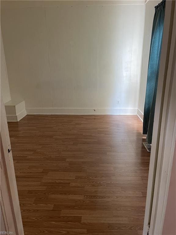 spare room featuring dark wood-style floors and baseboards