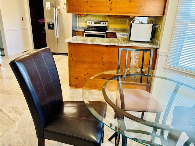 kitchen featuring appliances with stainless steel finishes, brown cabinets, a sink, and light stone counters