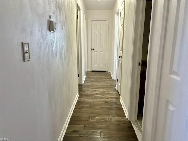 corridor featuring dark wood finished floors and baseboards