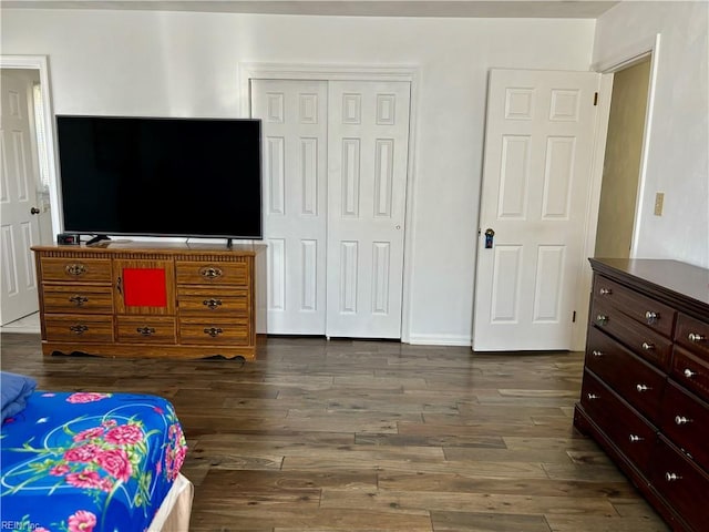 bedroom featuring dark wood-type flooring, a closet, and baseboards