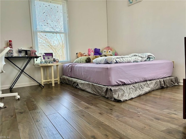 bedroom with wood-type flooring and baseboards