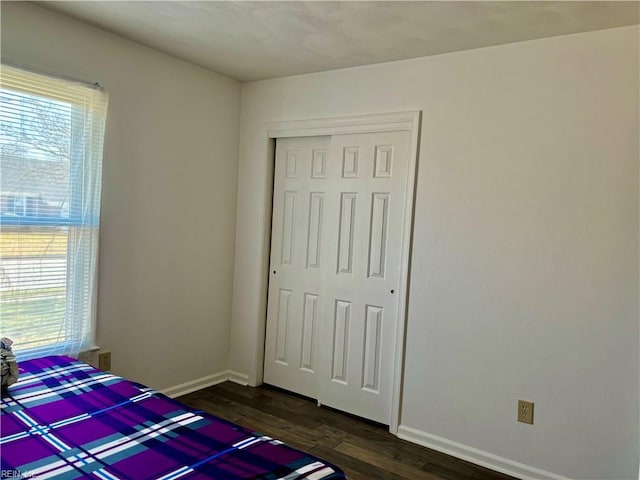 bedroom featuring a closet, dark wood-style flooring, multiple windows, and baseboards