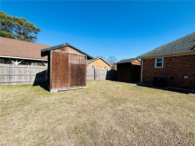 view of yard featuring an outbuilding, a storage unit, cooling unit, and a fenced backyard