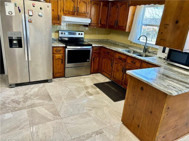 kitchen with brown cabinetry, a sink, stainless steel appliances, under cabinet range hood, and backsplash