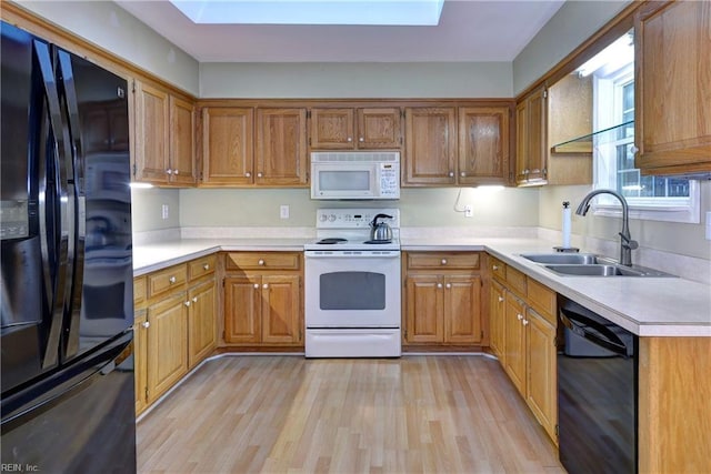 kitchen featuring a sink, light wood-style floors, light countertops, brown cabinets, and black appliances