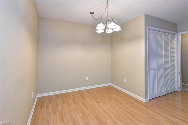 unfurnished room with light wood-style floors, baseboards, and a chandelier