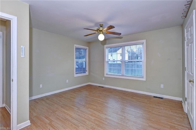 empty room featuring baseboards, ceiling fan, visible vents, and light wood-style floors