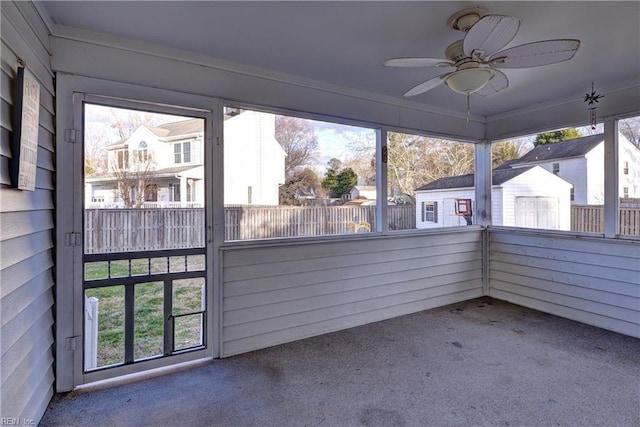 unfurnished sunroom with a ceiling fan and a residential view