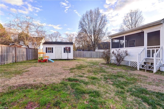 view of yard with a sunroom, a fenced backyard, an outdoor structure, and a storage shed