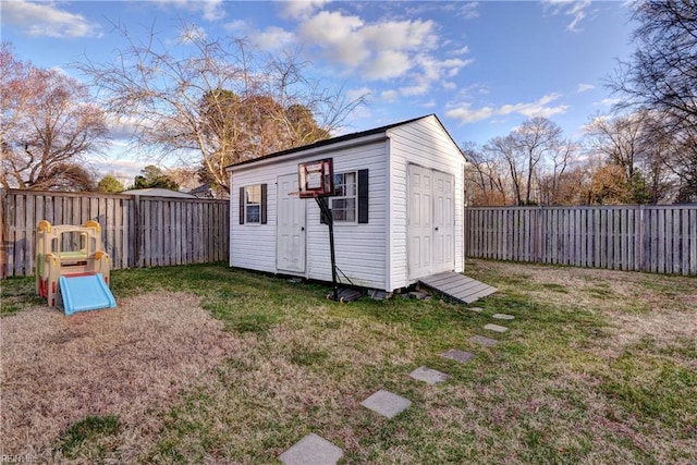 view of shed with a playground and a fenced backyard