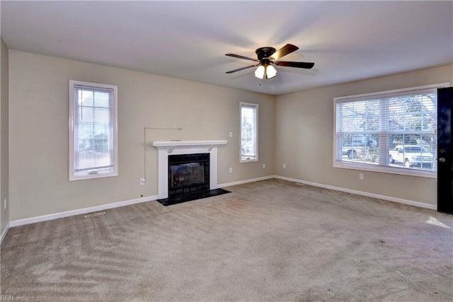 unfurnished living room with carpet, a fireplace with flush hearth, a ceiling fan, and baseboards