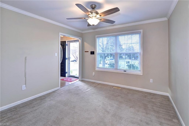 carpeted spare room featuring baseboards, a ceiling fan, and crown molding