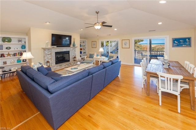 living area with lofted ceiling, light wood-style floors, a fireplace, and built in features