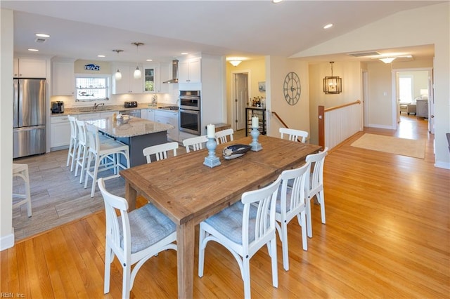 dining room featuring light wood-type flooring, a healthy amount of sunlight, vaulted ceiling, and recessed lighting