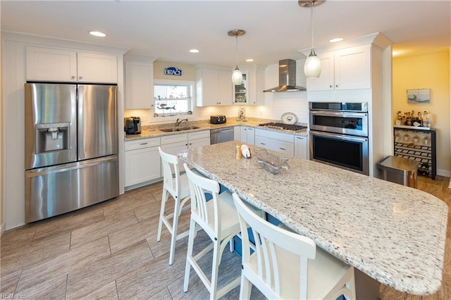 kitchen featuring a sink, white cabinets, appliances with stainless steel finishes, decorative backsplash, and wall chimney exhaust hood