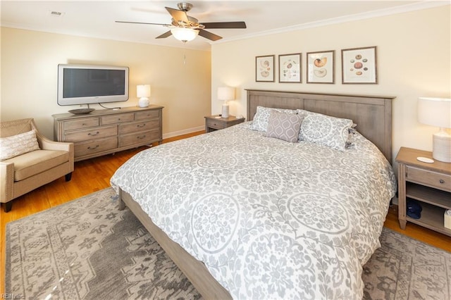 bedroom with visible vents, ornamental molding, a ceiling fan, wood finished floors, and baseboards