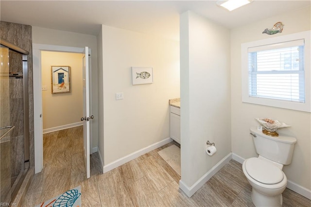 bathroom with toilet, vanity, wood finished floors, baseboards, and walk in shower