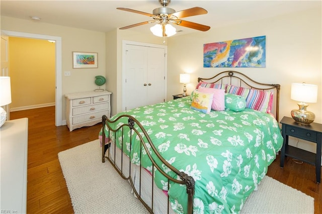 bedroom with a closet, wood finished floors, a ceiling fan, and baseboards