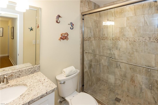 full bathroom featuring toilet, a stall shower, and vanity