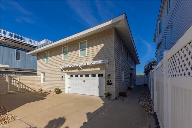 view of front of house featuring an attached garage, fence, and concrete driveway