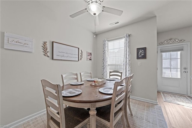 dining area featuring a ceiling fan, light wood-type flooring, visible vents, and baseboards