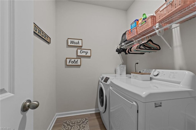 washroom with laundry area, baseboards, washing machine and clothes dryer, and wood finished floors