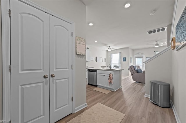 kitchen featuring visible vents, dishwasher, open floor plan, light wood-type flooring, and a sink