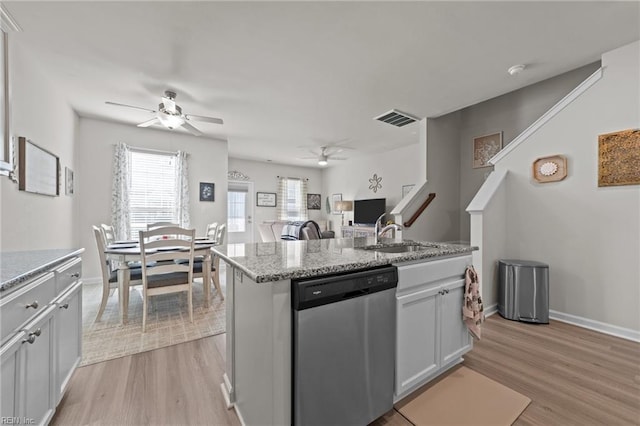 kitchen featuring light wood finished floors, stainless steel dishwasher, a sink, and visible vents