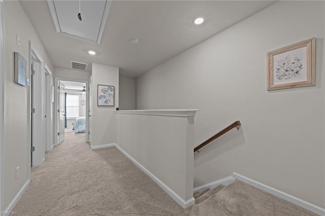 hall featuring carpet floors, visible vents, attic access, an upstairs landing, and baseboards