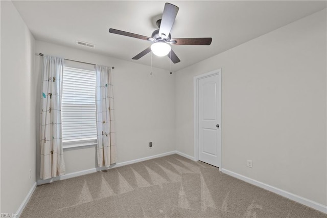 carpeted spare room featuring visible vents, baseboards, and ceiling fan