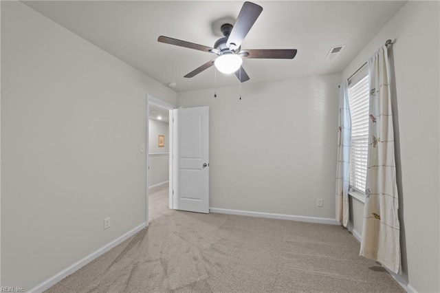 carpeted empty room featuring visible vents, baseboards, and a ceiling fan