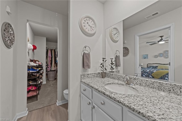 ensuite bathroom featuring visible vents, toilet, vanity, ensuite bath, and wood finished floors